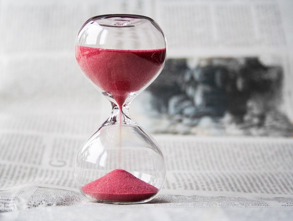 Image of a glass egg-timer with red sand running through it - more at the top than at the bottom